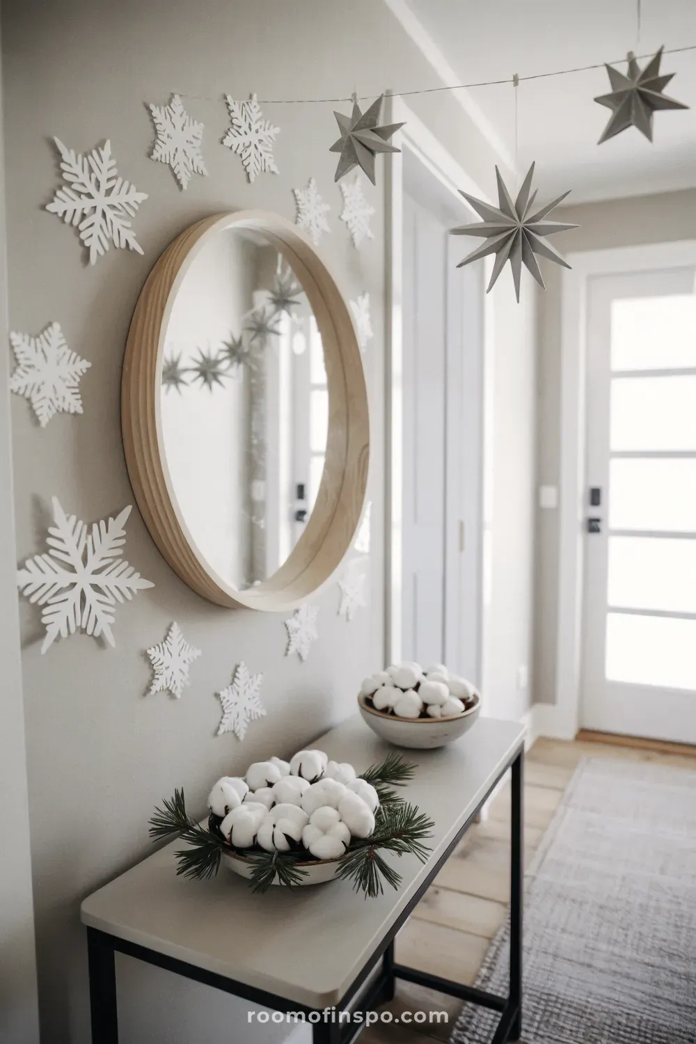 Entryway console table showcasing airy winter decor with snowflake wall art, cotton bolls, and geometric paper stars.