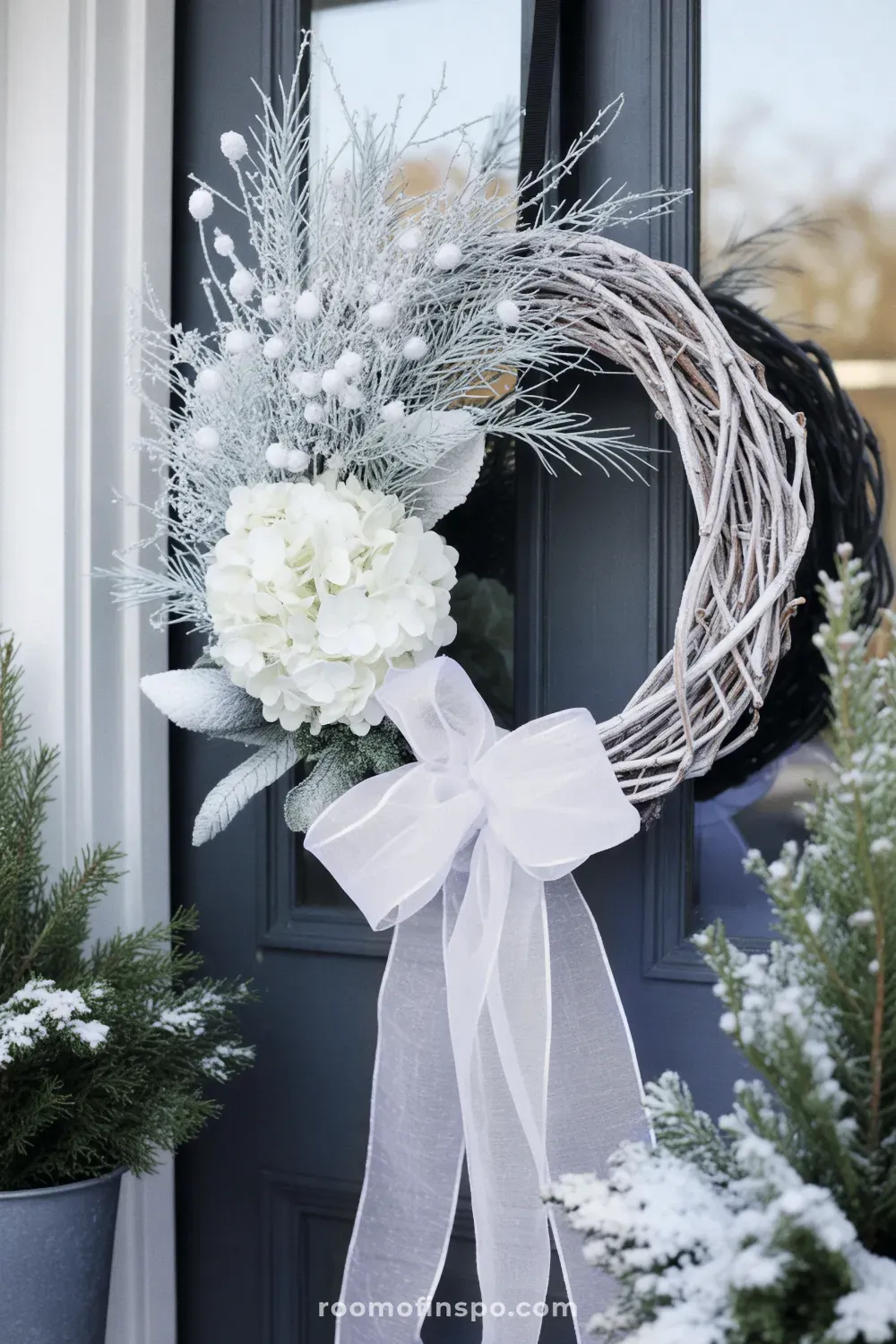A stunning all-white winter wreath with plush white flowers and ribbon accents, giving an ethereal and elegant snowy look.
