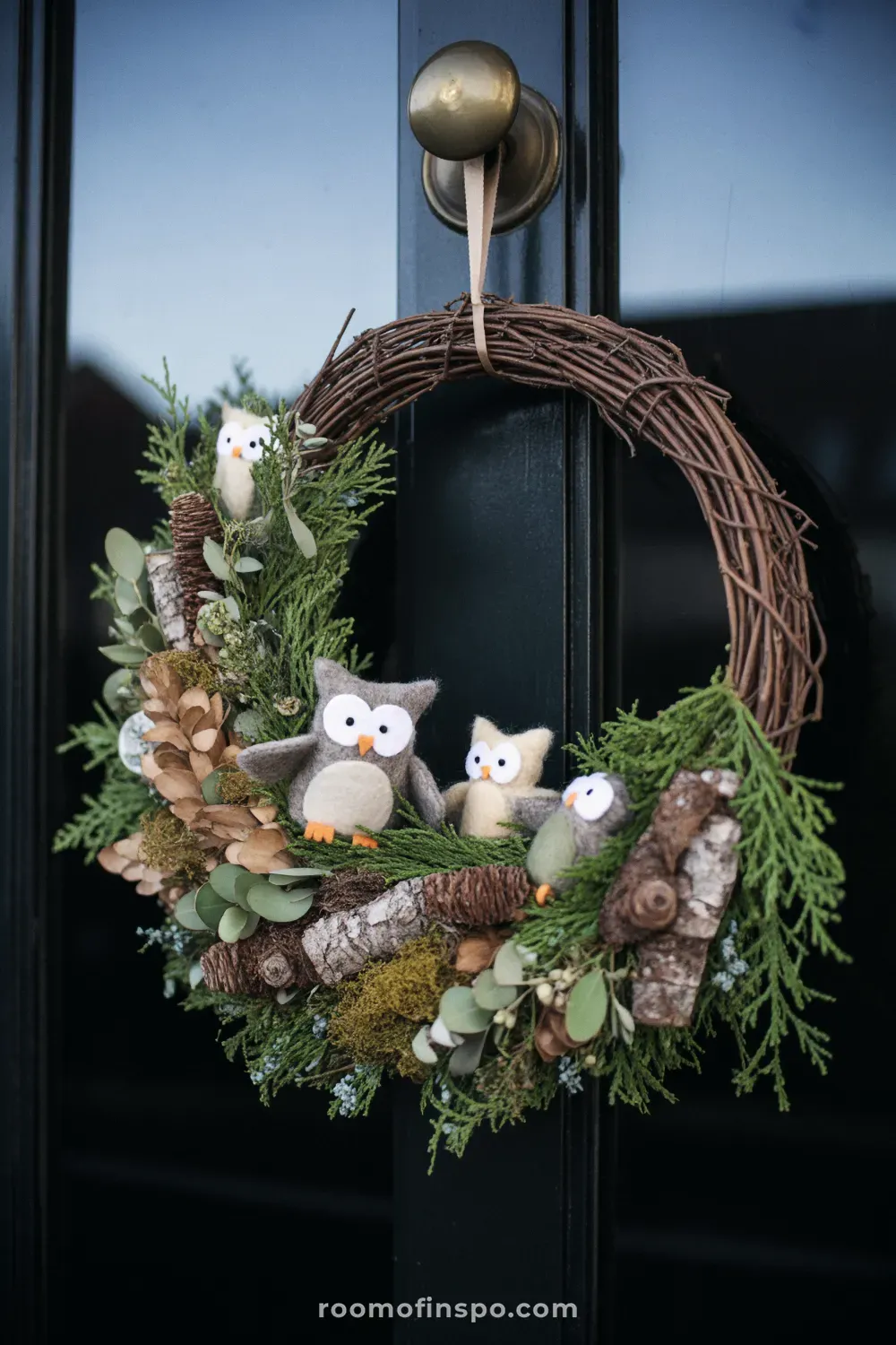 A dense, woodland-style winter wreath with dark green foliage, pinecones, and red berries, on a weathered brown door.
