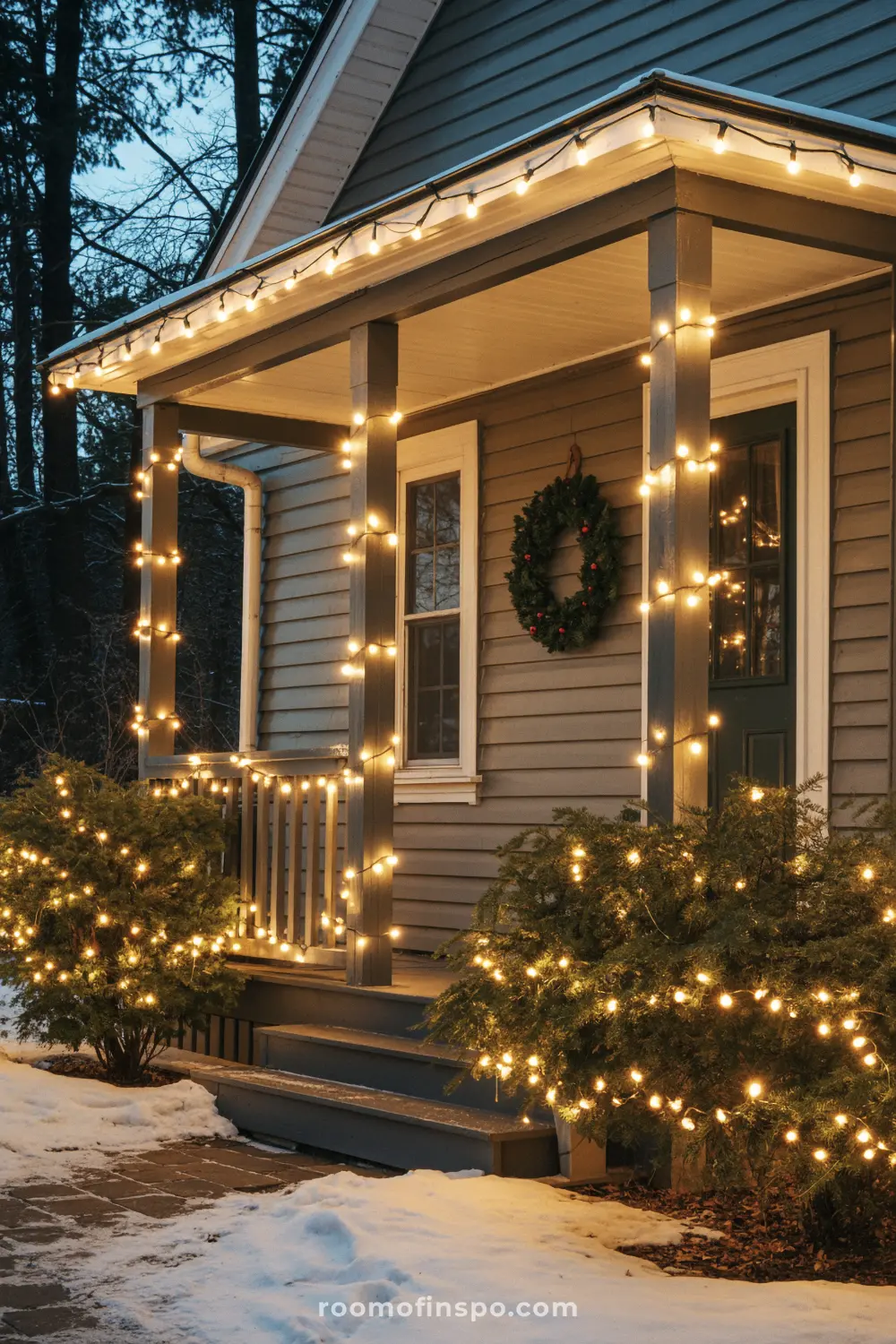 A traditional front porch decorated for Christmas with a wreath on the door and bright string lights.