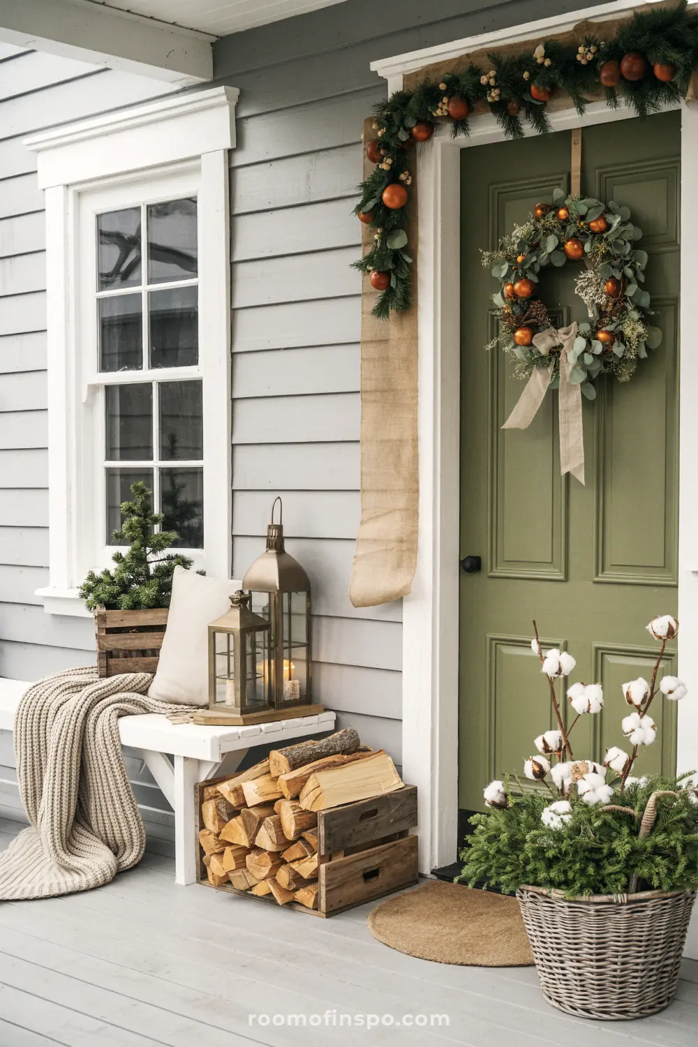 A rustic and natural front porch decorated for Christmas with firewood, a wreath, and a garland.
