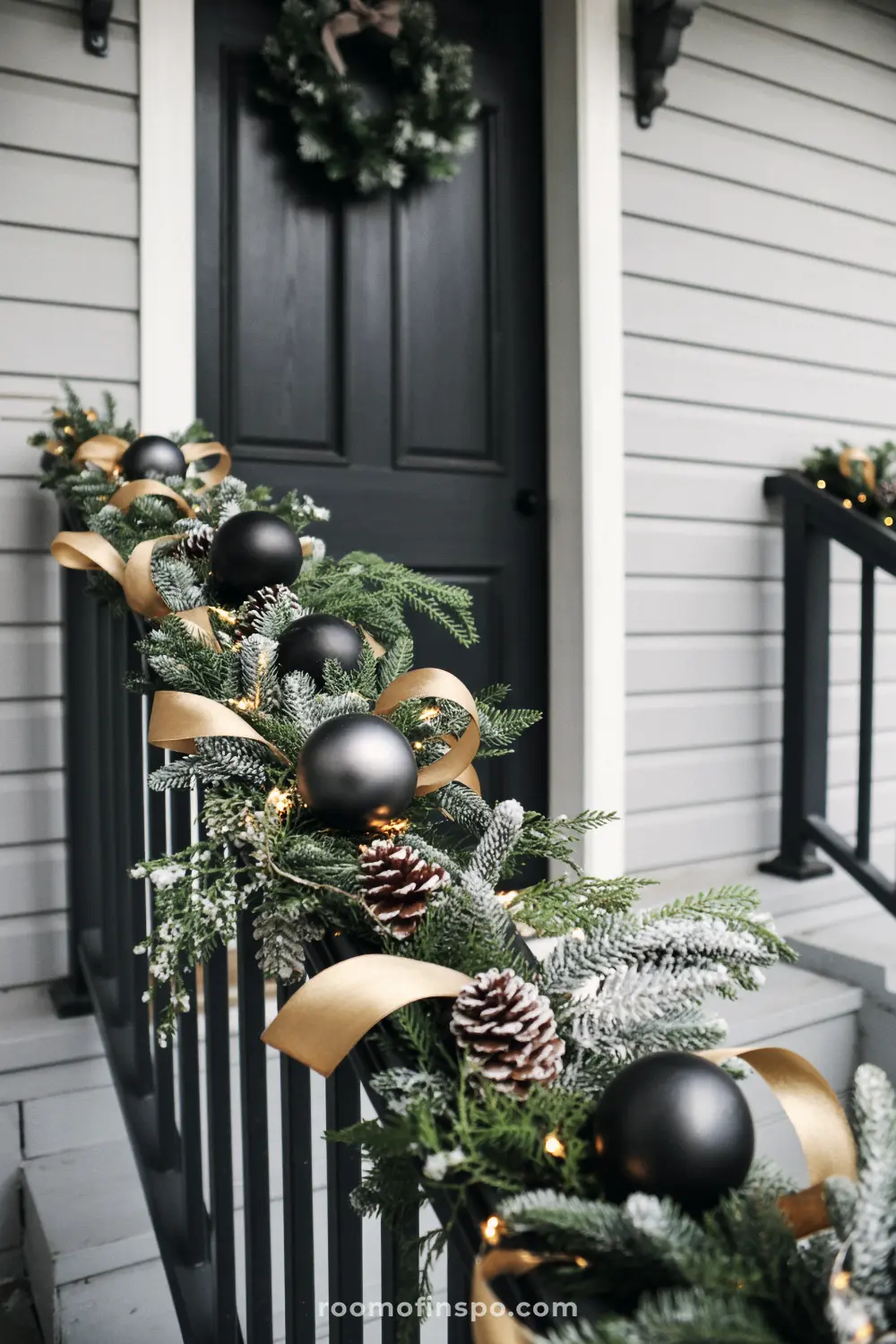 A sleek front porch decorated with a Christmas garland featuring black ornaments and gold ribbon.