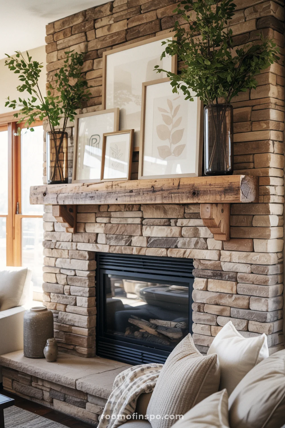 Stacked stone fireplace with reclaimed wood mantel, neutral leaning art, glass vases, and greenery.