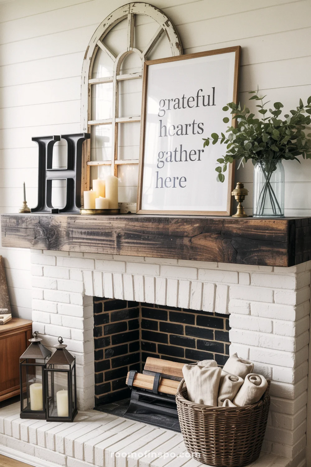 White brick fireplace with dark wood mantel, arched window decor, candles, lanterns, and greenery.
