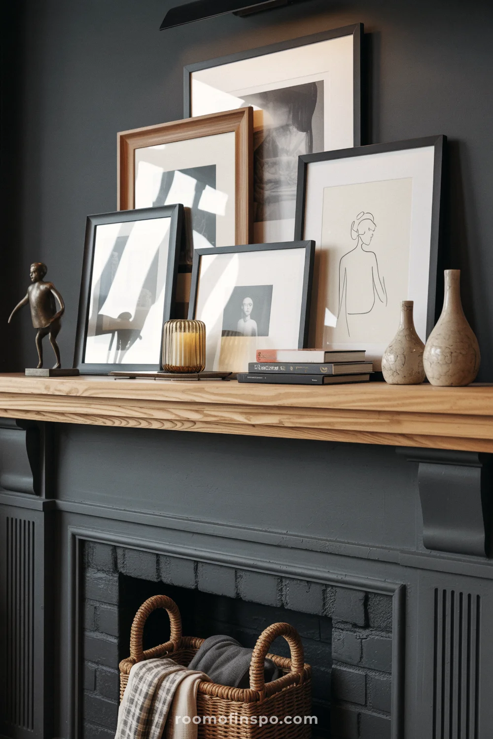 Charcoal surround with oak mantel, layered gallery frames, small sculpture, vases, and stacked art books.